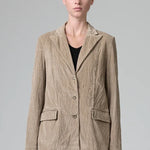Front view of camel regular fit jacket on  model wearing camel pants and black top, against a grey background.