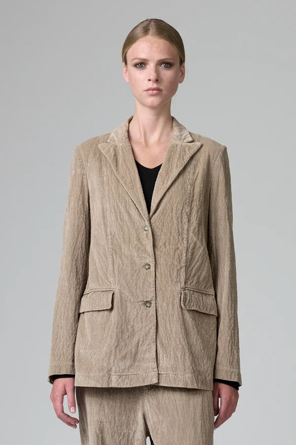 Front view of camel regular fit jacket on  model wearing camel pants and black top, against a grey background.