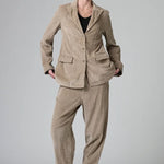 Front view of camel regular fit jacket on model wearing camel pants and black top with boots, against a grey background.