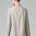 Back view of chalk herringbone jacket on model wearing chalk pants, against a grey background.