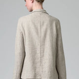 Back view of chalk herringbone jacket on model wearing chalk pants, against a grey background.