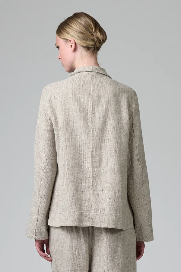 Back view of chalk herringbone jacket on model wearing chalk pants, against a grey background.