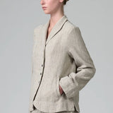 Side view of chalk herringbone jacket on model wearing chalk pants, against a grey background.