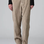 Front view of camel regular fit trousers on model wearing black top and boots, against a grey background.