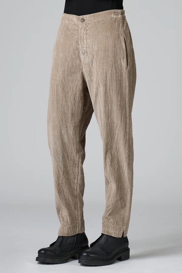 Side view of camel regular fit trousers on model wearing black top and boots, against a grey background.