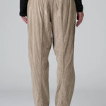 Back view of Camel Regular fit trousers on model wearing black top and boots, against a grey background.