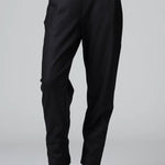 Front view of black slim fit trousers on model wearing black top and boots, against a grey background.