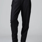 Front view of black slim fit trousers on model wearing black top and boots, against a grey background.