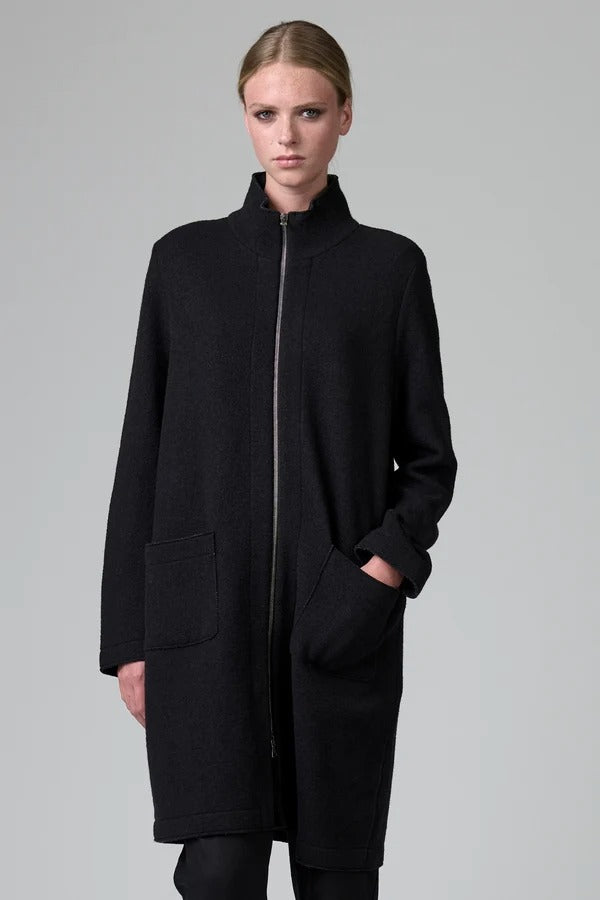 Front view of black/anthracite straight coat on model wearing black pants, against a grey background.