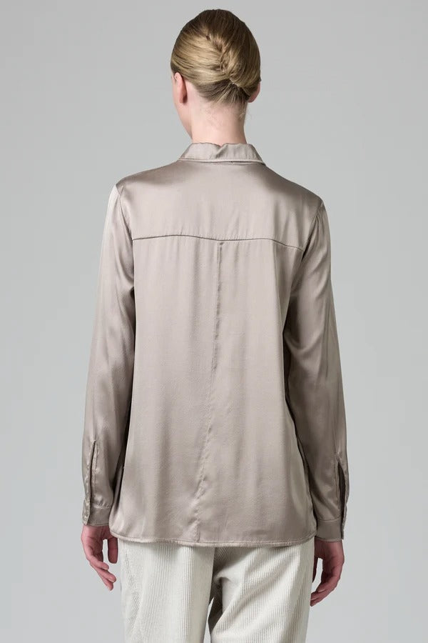 Back view of stone stretch silk satin regular fit shirt on model wearing chalk pants against a grey background 