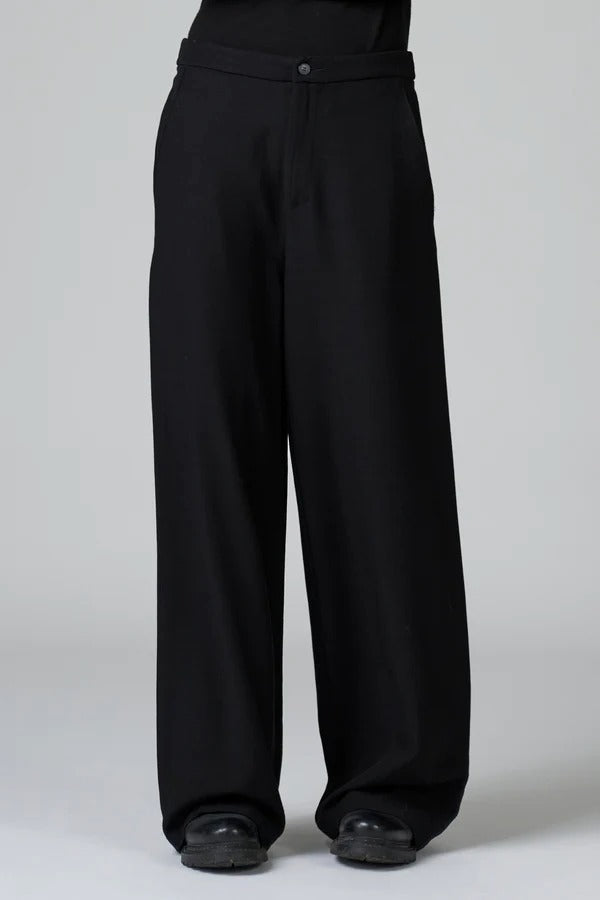 Front view of black stretch wide leg trousers on model wearing black top and boots, against a grey background.