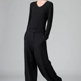 Front view of black stretch wide leg pants on model wearing black top and boots, against a grey background.