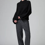 Front view of black wool chain stitch knit ribbed turtleneck on model wearing grey pants, against a grey background.