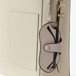 Back alternate view of nude glasses case with lanyard on white bag, against white background, with no model shown.