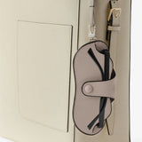 Back alternate view of nude glasses case with lanyard on white bag, against white background, with no model shown.