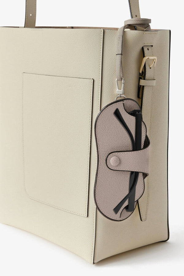 Back alternate view of nude glasses case with lanyard on white bag, against white background, with no model shown.