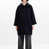 Front view of black bonnet drivers down coat on model wearing grey pants, against a white background.