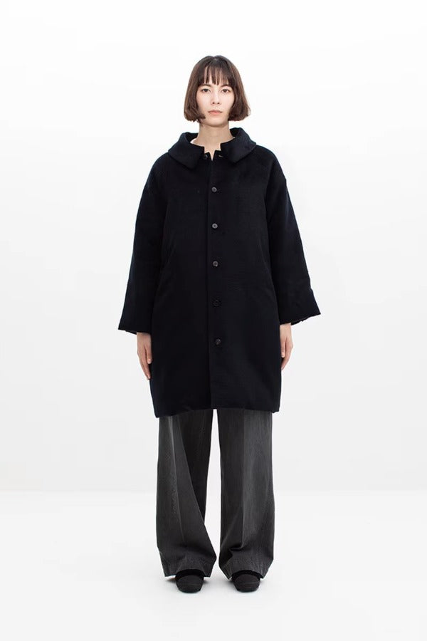 Front view of black bonnet drivers down coat on model wearing grey pants, against a white background.