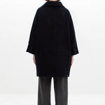 Back view of black bonnet drivers down coat on model wearing grey pants, against a white background.