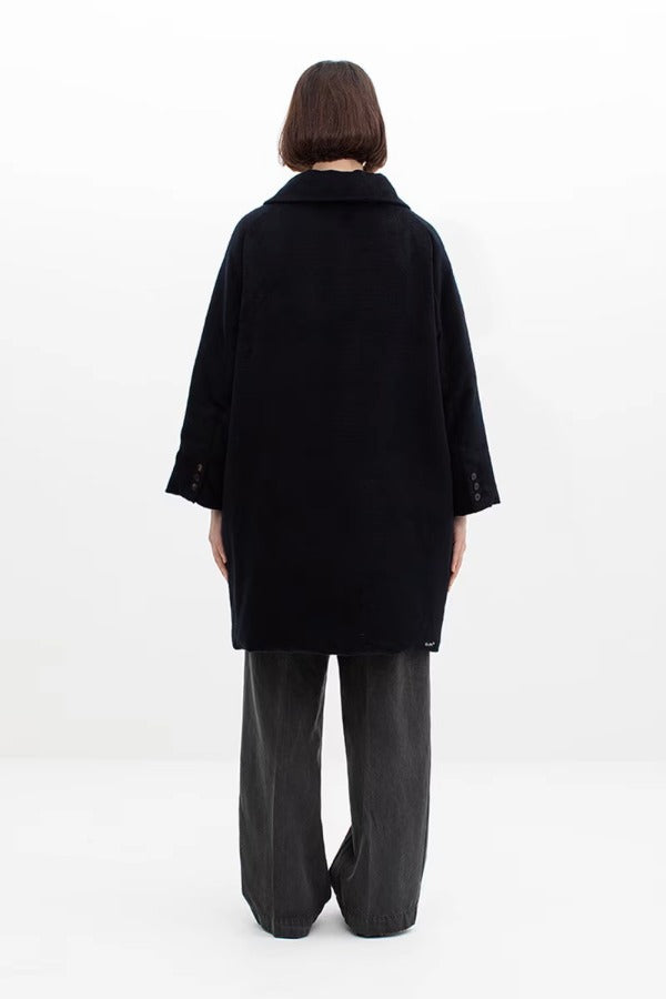 Back view of black bonnet drivers down coat on model wearing grey pants, against a white background.