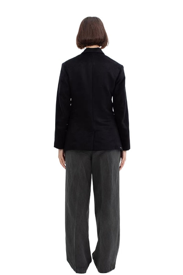 Back view of black sabrina db jacket on model wearing grey pants, against a white background.