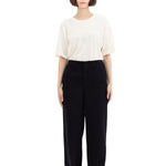 Front view of black wide silk pants on model wearing white t-shirt and sneakers, against a white background.