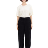 Front view of black wide silk pants on model wearing white t-shirt and sneakers, against a white background.