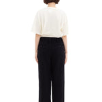 Back view of black wide silk pants on model wearing white t-shirt and sneakers, against a white background.
