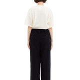 Back view of black wide silk pants on model wearing white t-shirt and sneakers, against a white background.