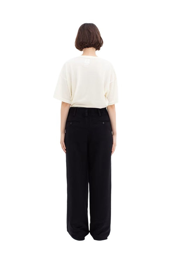 Back view of black wide silk pants on model wearing white t-shirt and sneakers, against a white background.